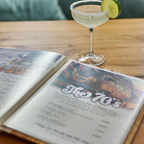 Aufgeschlagene Cocktailkarte im EIX. Finden Sie innerhalb der Dekaden den passenden Cocktail für Sie.